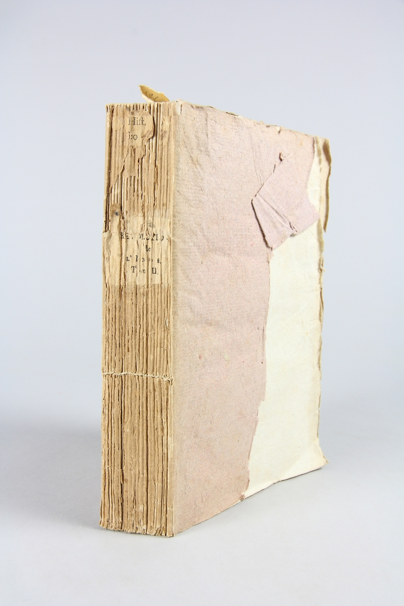 Bok, pappband, "Révolutions de l´Inde", del 2, tryckt 1796 i Paris. Pärmar av ljusbrunt papper, blekt rygg med tryckta etiketter med bokens titel och nummer, otydlig text. Skuret snitt.