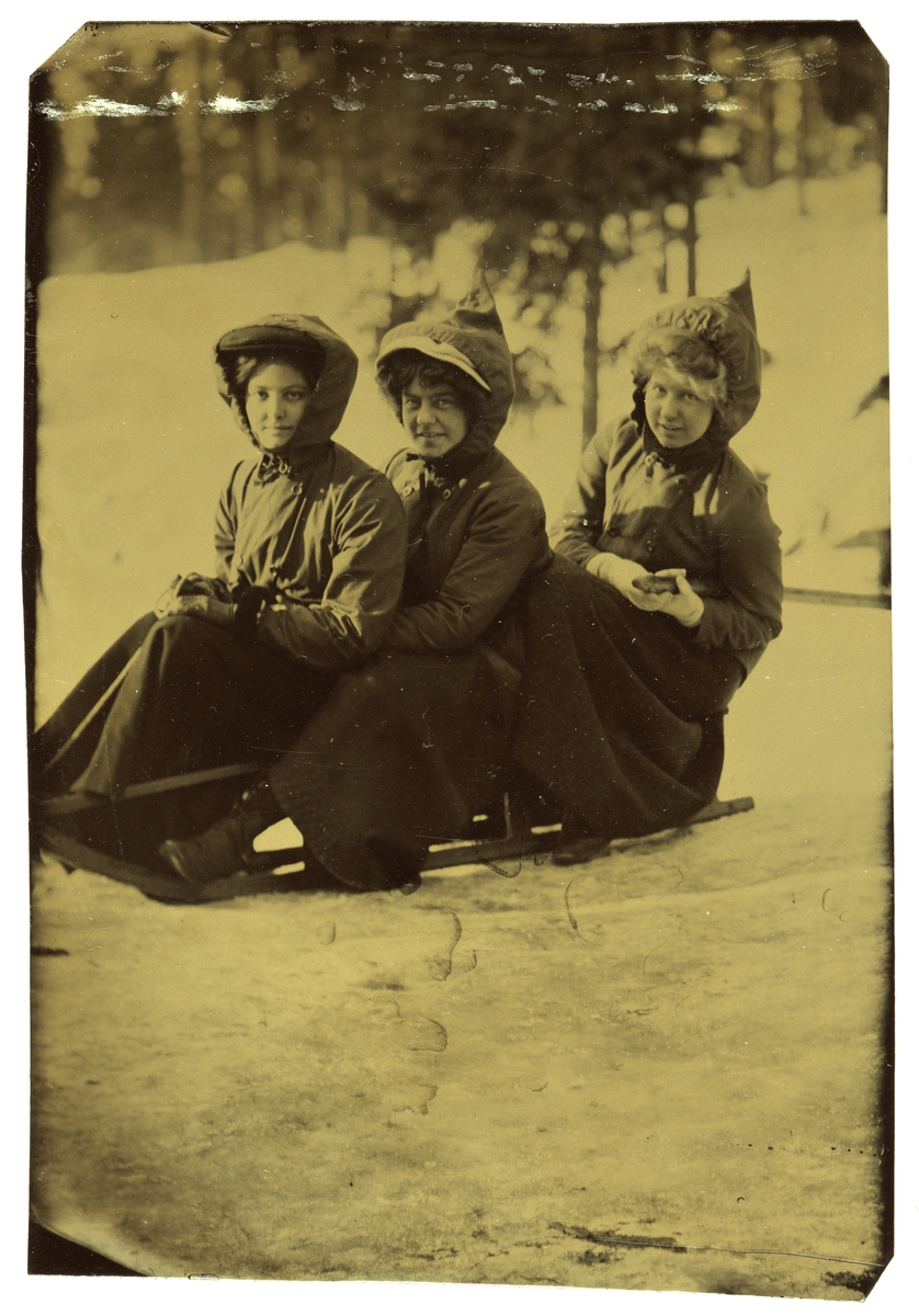 Betsy Gude (Schirmer) med venninner på en kjelke i Holmenkollen. 

Foran sitter Stephanie Banks fra Irland, en ukjent pike i midten og Betsy bakerst.