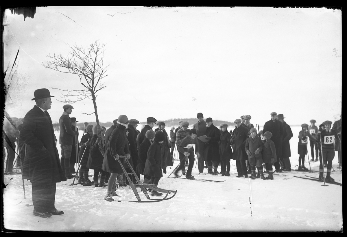 Åskådare och tävlande fotograferade vid starten av en skidtävling.