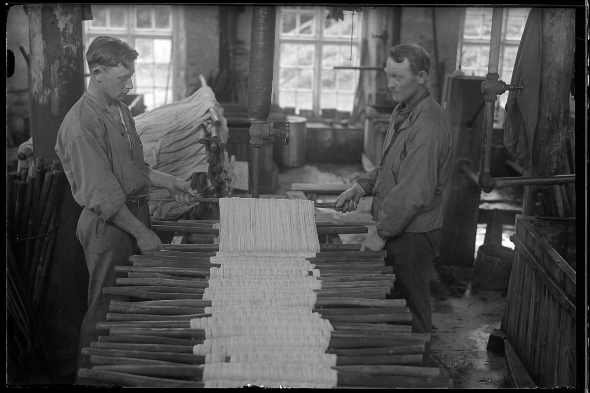 Verksamhetsbild från Nääs Fabriker där två personer arbetar med garnhärvor vid ett bord.