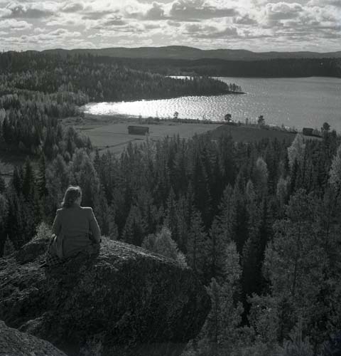 En kvinna sitter på en höjd och ser ut över en sjö, 1947.