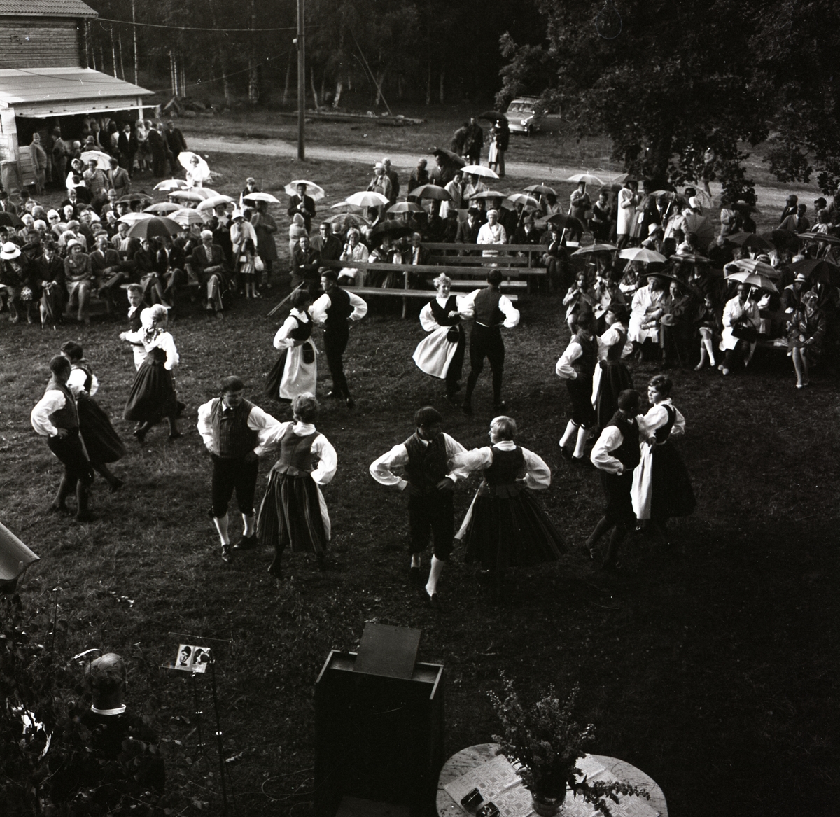 Ringdans vid hembygdsgården i Rengsjö inför en publik som står under paraplyer.