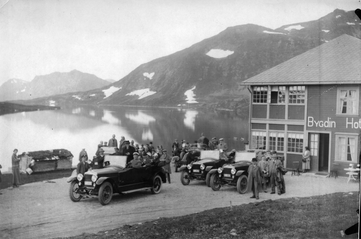 Biler og mennesker utenfor Bygdin Høyfjellshotell i 1930-åra. Innsjøen Bygdin midt i bildet.