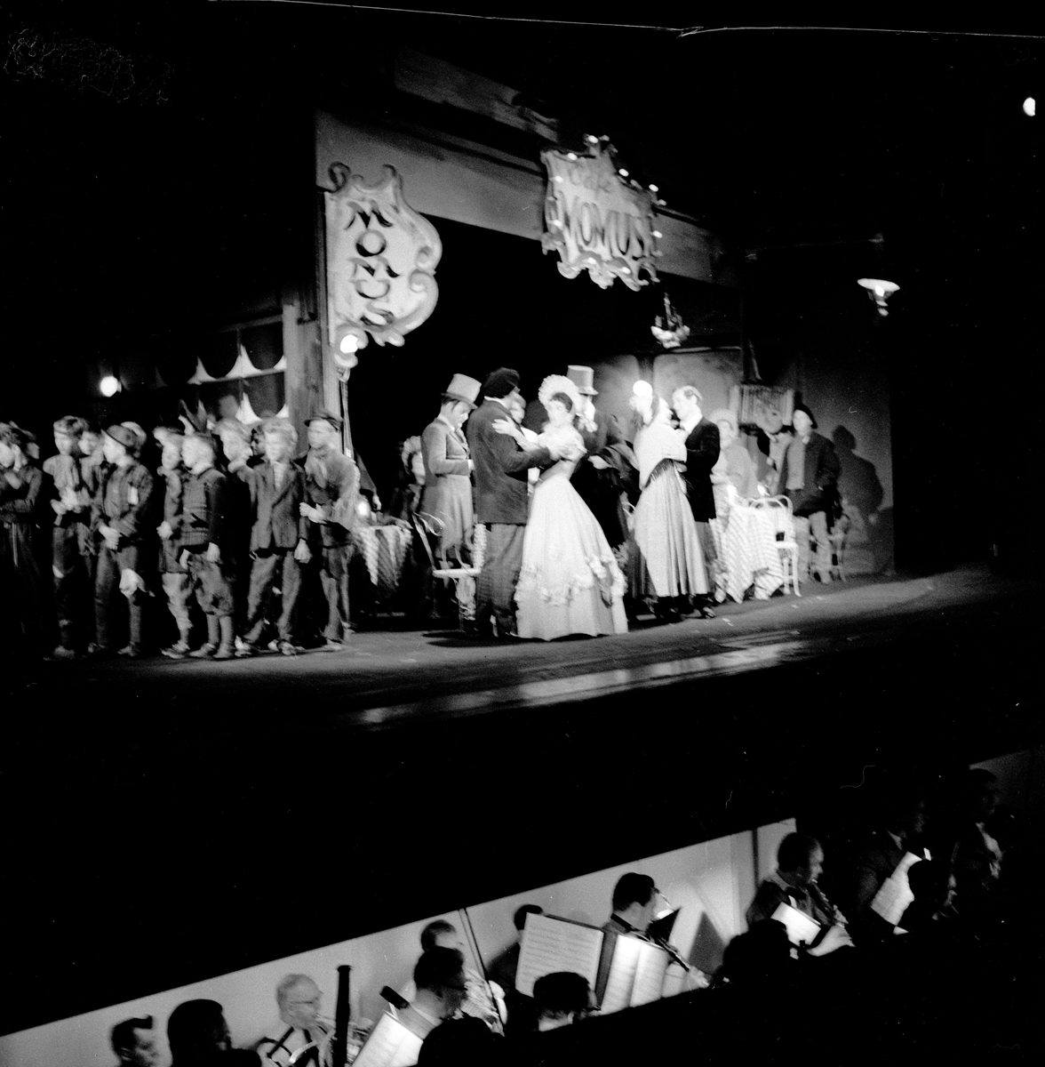 Oppsetningen av operaen "La Boheme" på Folketeatret. Voksne og barn sammen på scenen, ser litt av orkestergrava. Fotografert 6. november 1956.