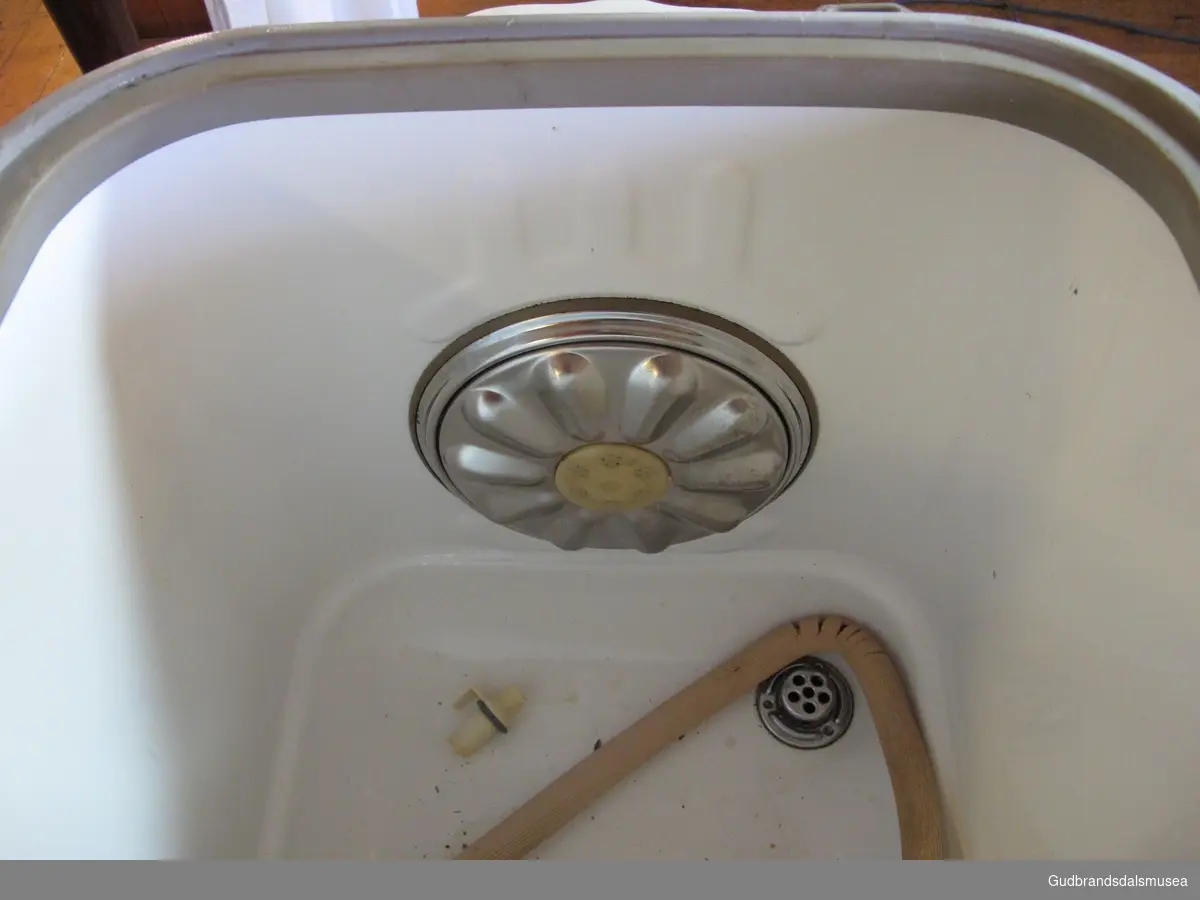 Elektrisk vaskemaskin med lokk på toppen. Merket Evalet. På baksiden er det to brytere. En for varme og en for motor. Nede i maskinen er det en rotor - formet som et tett hjul. Slangen for tapping av vann er brekt av.  Maskinen er emaljert. Har  et rødt "øye" på baksiden. En vaskestav følger med.