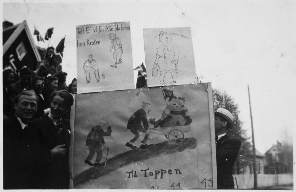 Frigjøringsdagen. Ungdom med plakater på skoleplassen. "E vil fan ikke dø lamma hain Kroken", "Til Toppen"