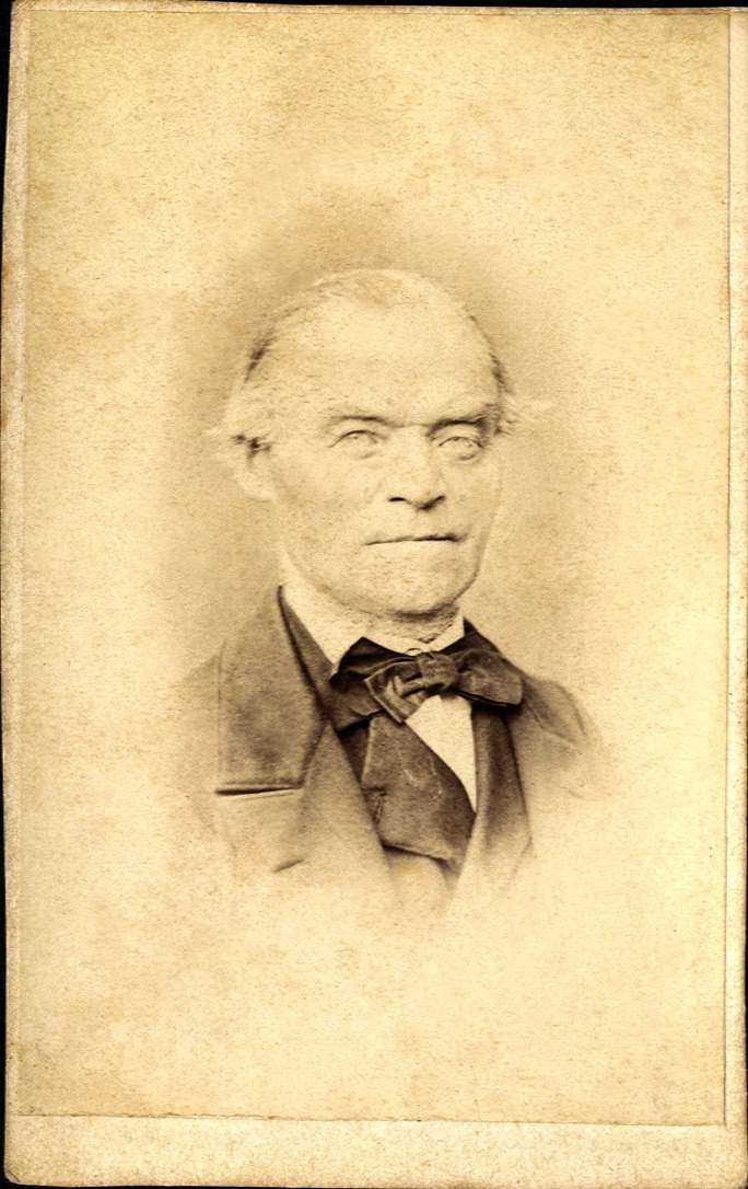 Porträtt (bröstbild, halvprofil) av en okänd äldre man i kostym med väst och stärkkrage med fluga. 

Bildtext:(baksidan) ej text