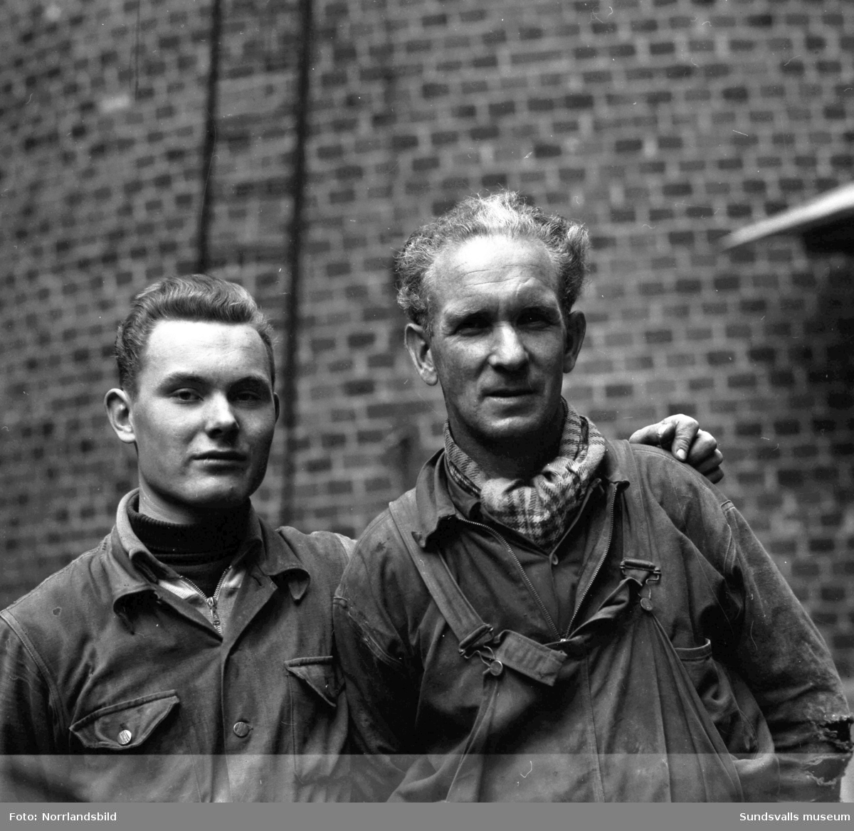Två män vid Östrandsfabrikens skorsten.