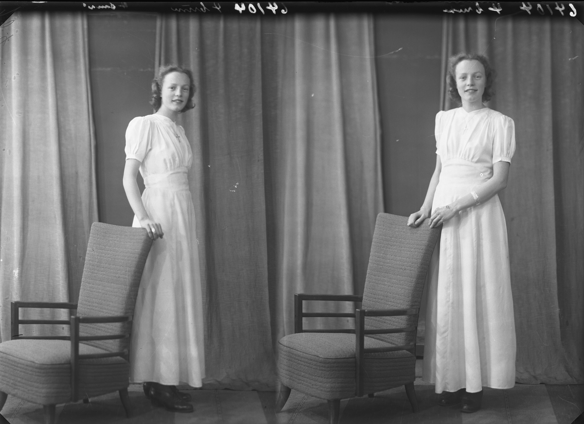 Portrett. Ung kvinne i lang lys kjole. Poserer med en stol. Konfirmant. Bestilt av Ingrid Johansen. Grenseplas 10