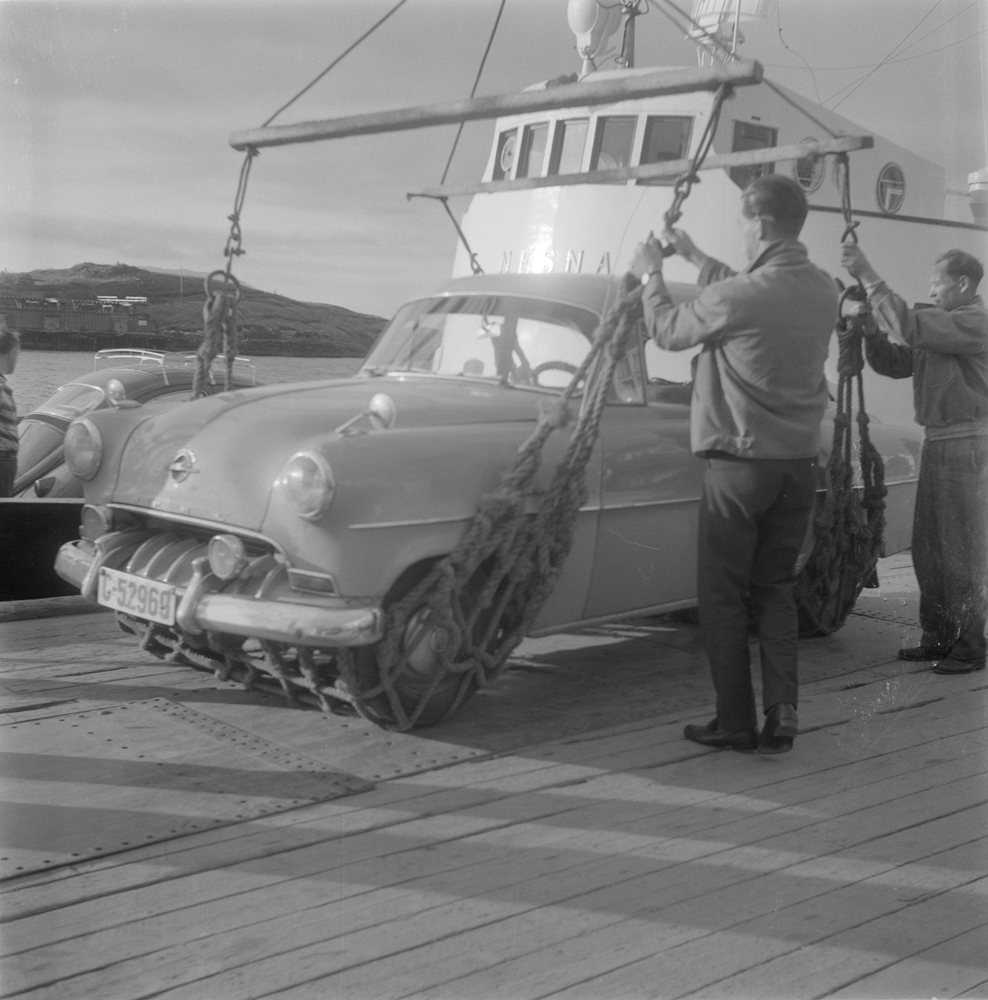Biler som blir heist på land fra lokalbåten M/S Nesna. 
Bilen er reg. i Akershus (C-52569) og er en Opel Rekord 1953-54.