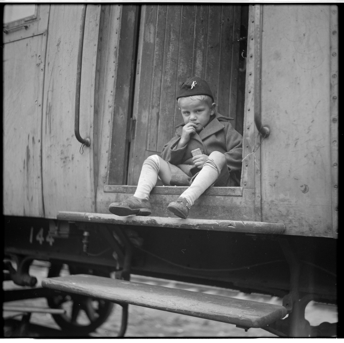 Okänd pojke sitter på avsatsen sitter till Statens Järnvägar, SJ Bostadsvagn 144.