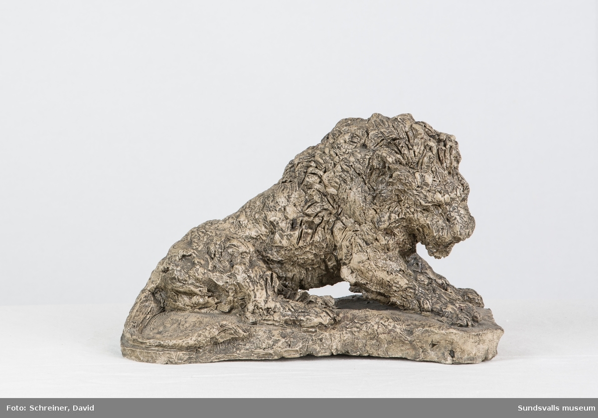 En patinerad gips skulptur i from av ett gammalt lejon med kraftig man.