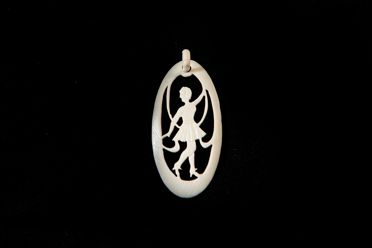 Ett hängsmycke av ben, ovalt formad föreställande en siluett av den dansande flicka.