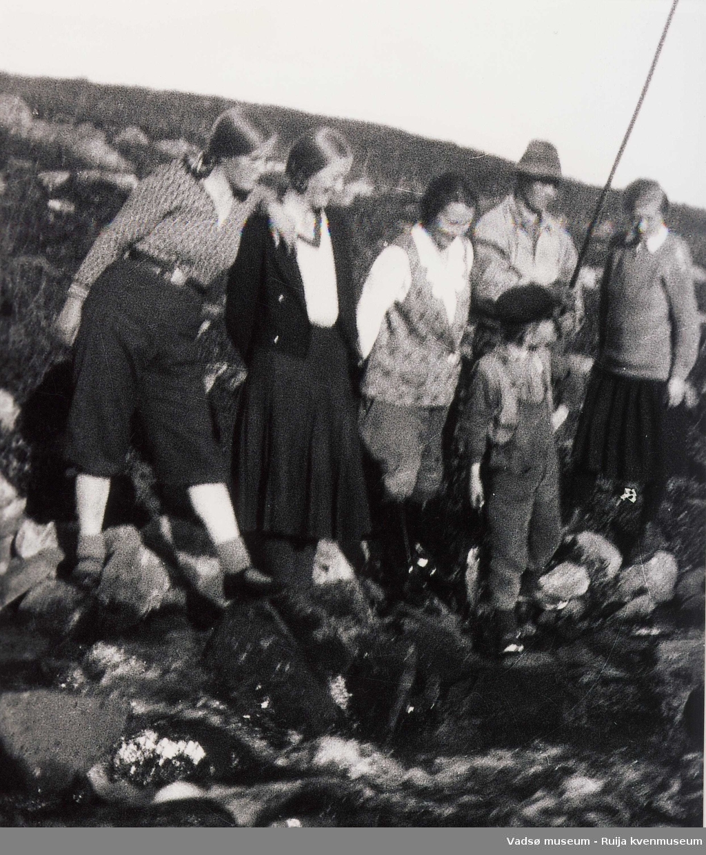 En gruppe damer og fiskere står ved elva.Nummer to fra venstre antatt Rikarda Wara, Celine Espejord i midten og Belgosmaja. Helt til høyre en ukjent fisker og gutt som står foran. Ca 1950-tallet