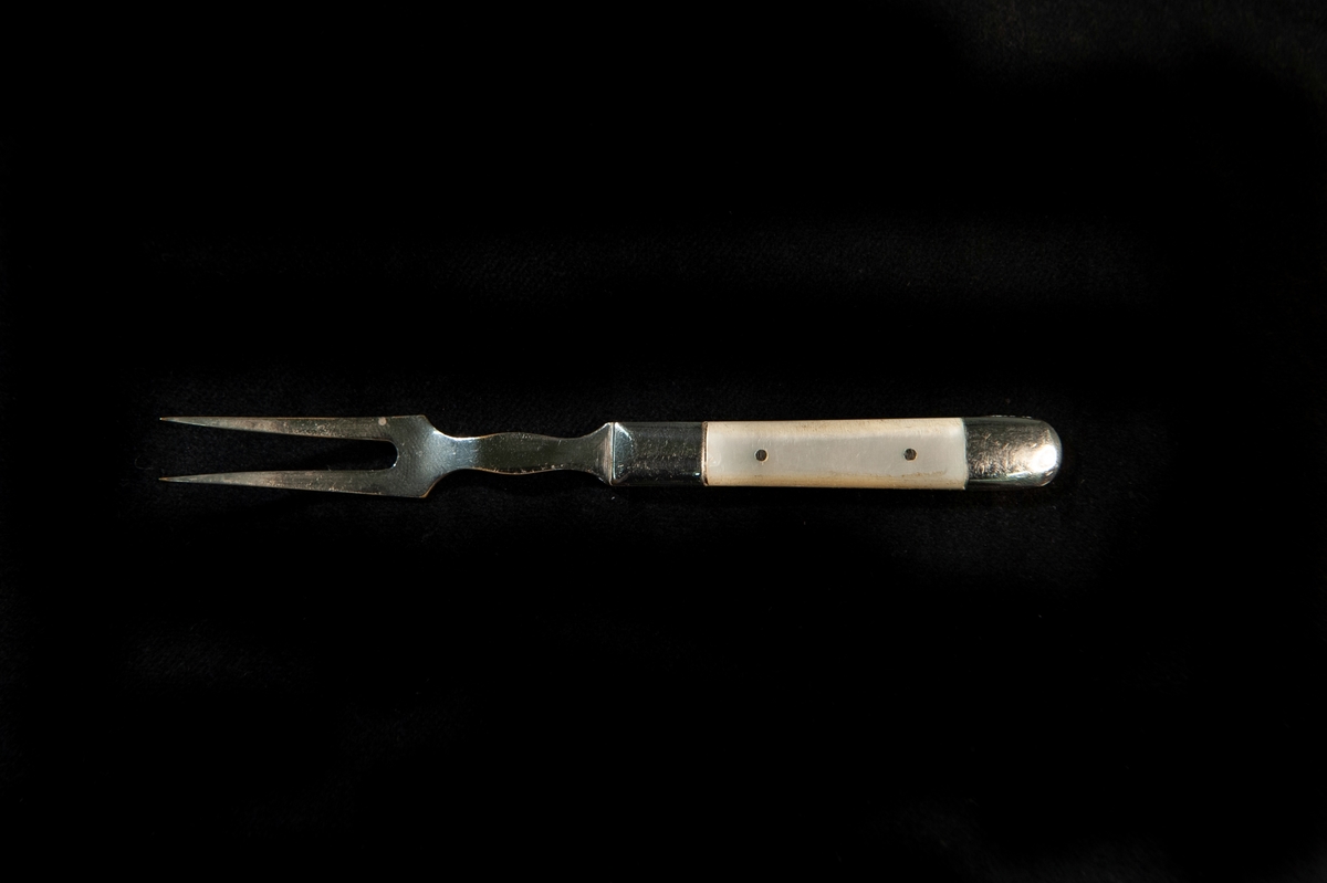 En liten tvåtenad gaffel av nickel. Inläggning av pärlemo påskaftet.Saknar helt stämplar.