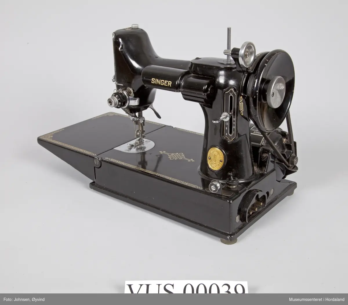 Komplett symaskin med diverse utstyr i svart kasse. I bruksanvisning står Singer Featherweight 221 K Portable Sewing Machine.