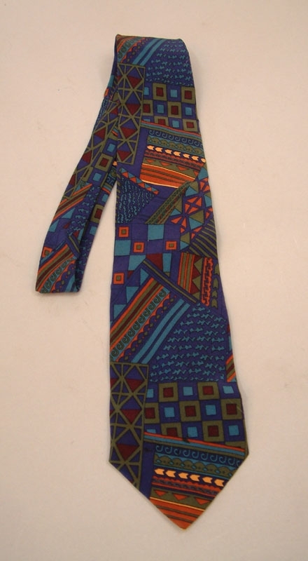 Flerfärgad slips, mönstrad i röda, orange, gula mm ränder, rutor, trekanter på blå botten.