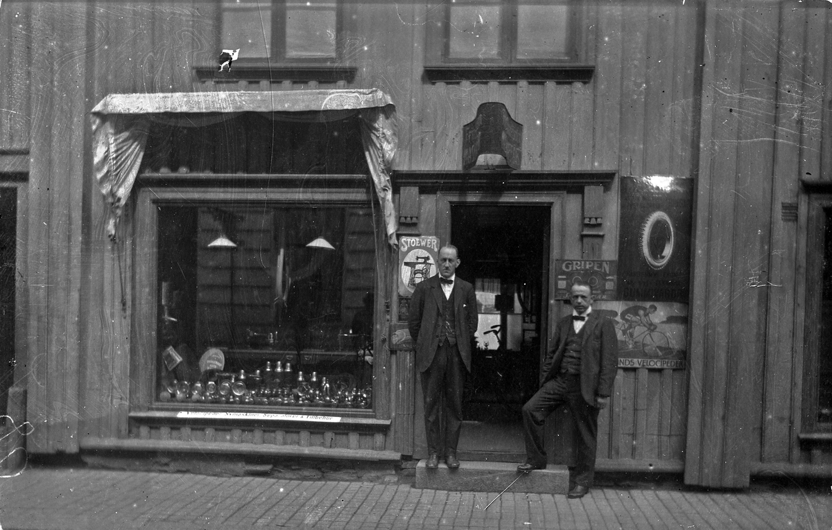 Exteriörbild från Fritz Johanssons maskinaffär som låg på Kungsgatan 28, Alingsås (Nygrens fastighet). Vid ingången står (från vänster) Claes Hallberg och Fritz Johansson.