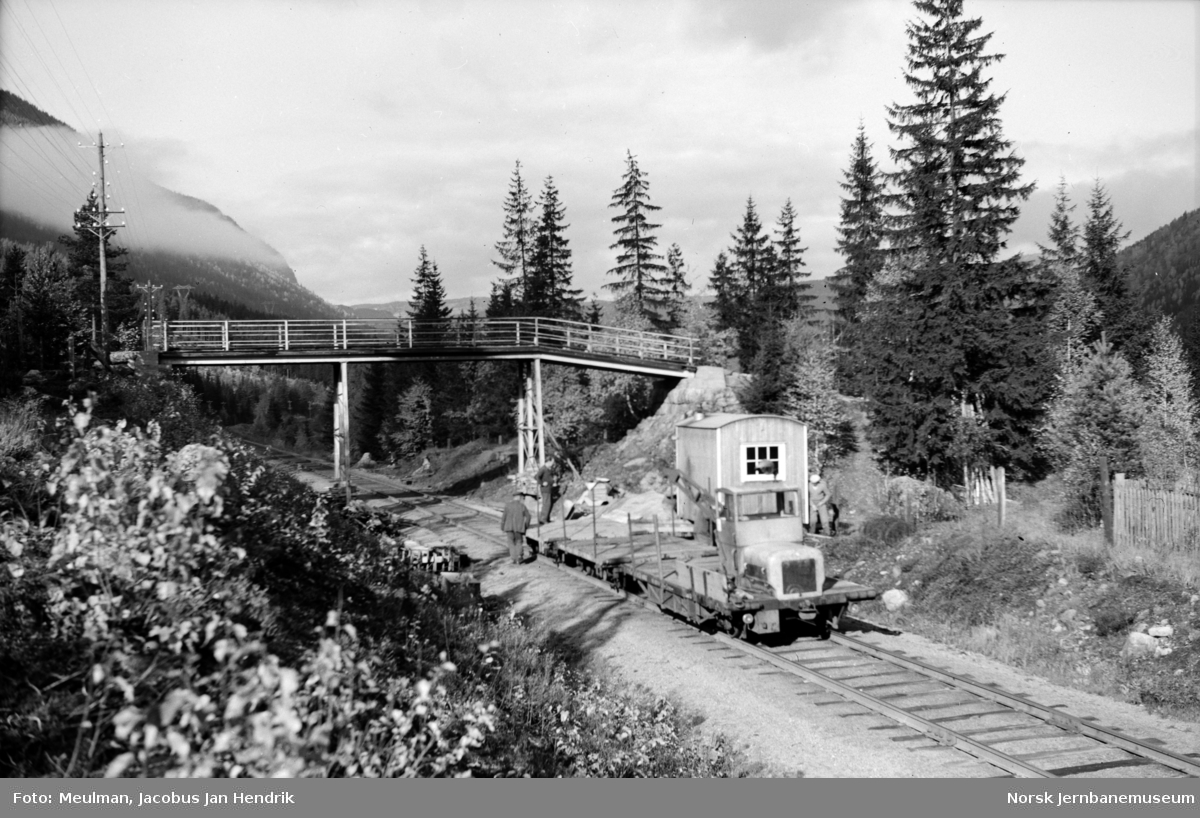 Arbeid med heving av overgangsbro ved Svenkerud km 196,11 i forbindelse med elektrifiseringen av Bergensbanen. Arbeidstrallen litra Robel 10 ble benyttet til transport av materialer.