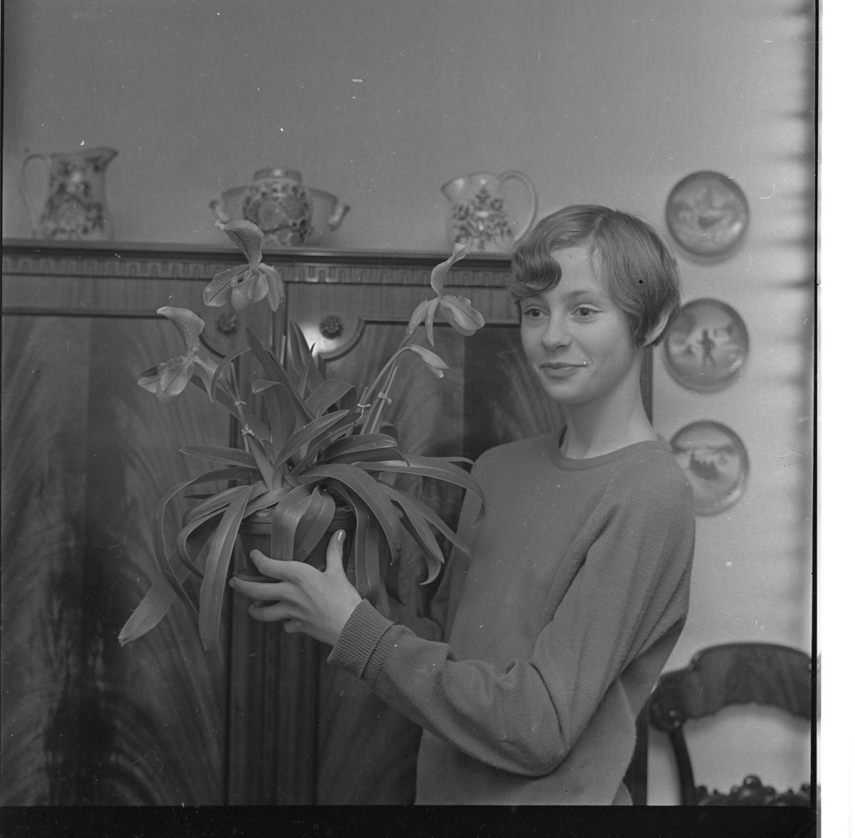 Elisabeth Josefsson står framför ett linneskåp med en orkidé i famnen.