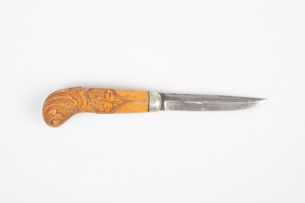 En liten kniv med skaft av tre og knivblad av metall. Treverket er utsmykket med utskjæringer av akantus. Skaftet har et rundt buet hode i enden.