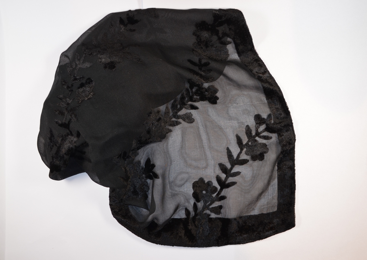 Lite, sort sjal etter Eva Scheer. Med blomsterornamenter.