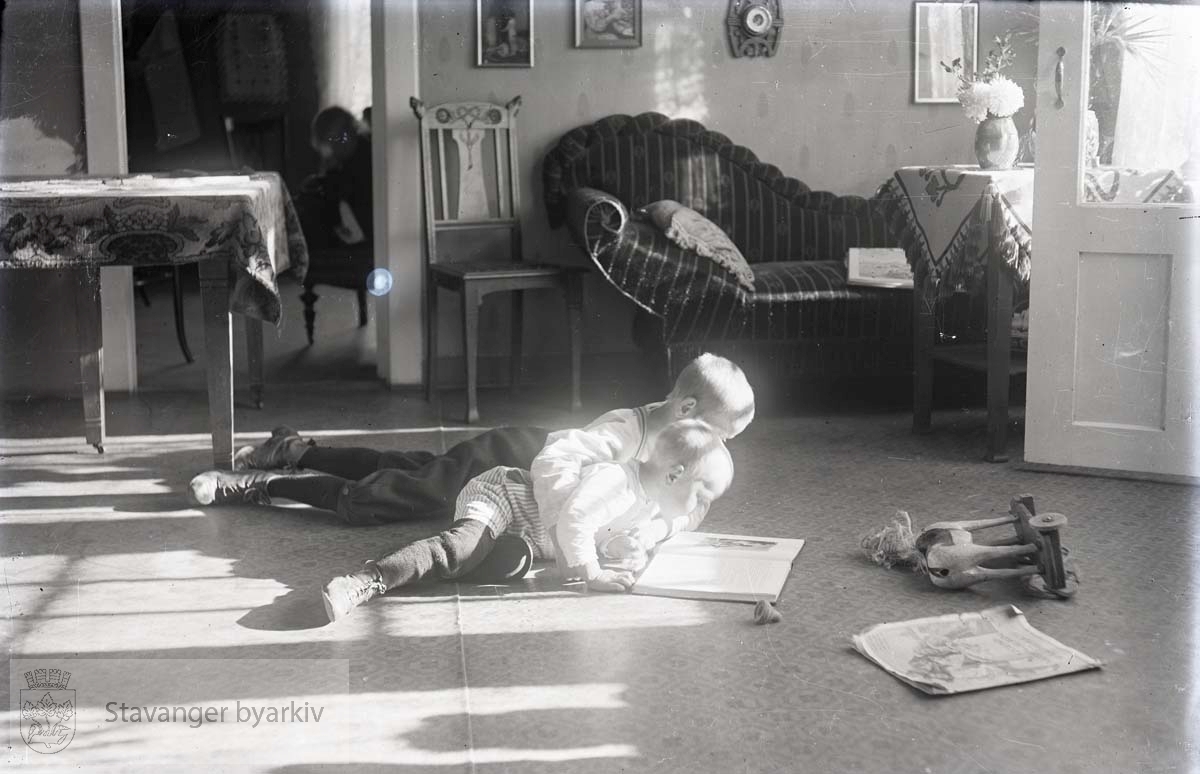 To gutter ligger på gulvet og leser