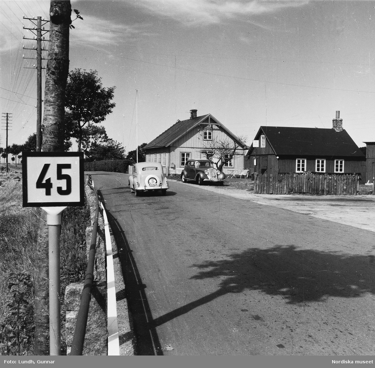 En väg i Skåne år 1952. Till vänster en Opel Olympia årsmodell  och till höger vid sidan av vägen en Hupmobile Aerodynamic årsmodell 1934.