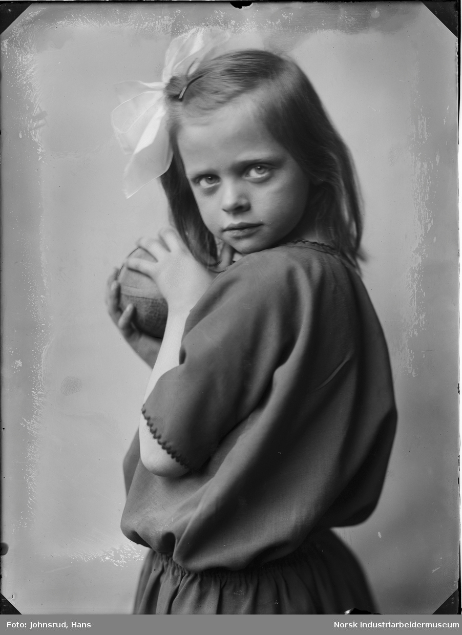 Portrett av jente med ball i hendene og sløyfe i håret.