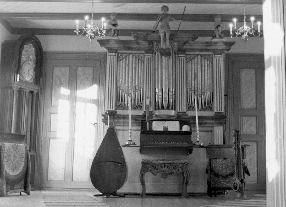 Sentralt i bildet står Lade/Vollanorgelet fra slutten av 1830-årene. Til venstre for orgelet står det en cecilium, sannsynligvis fransk, fra siste halvdel av 1800-tallet.