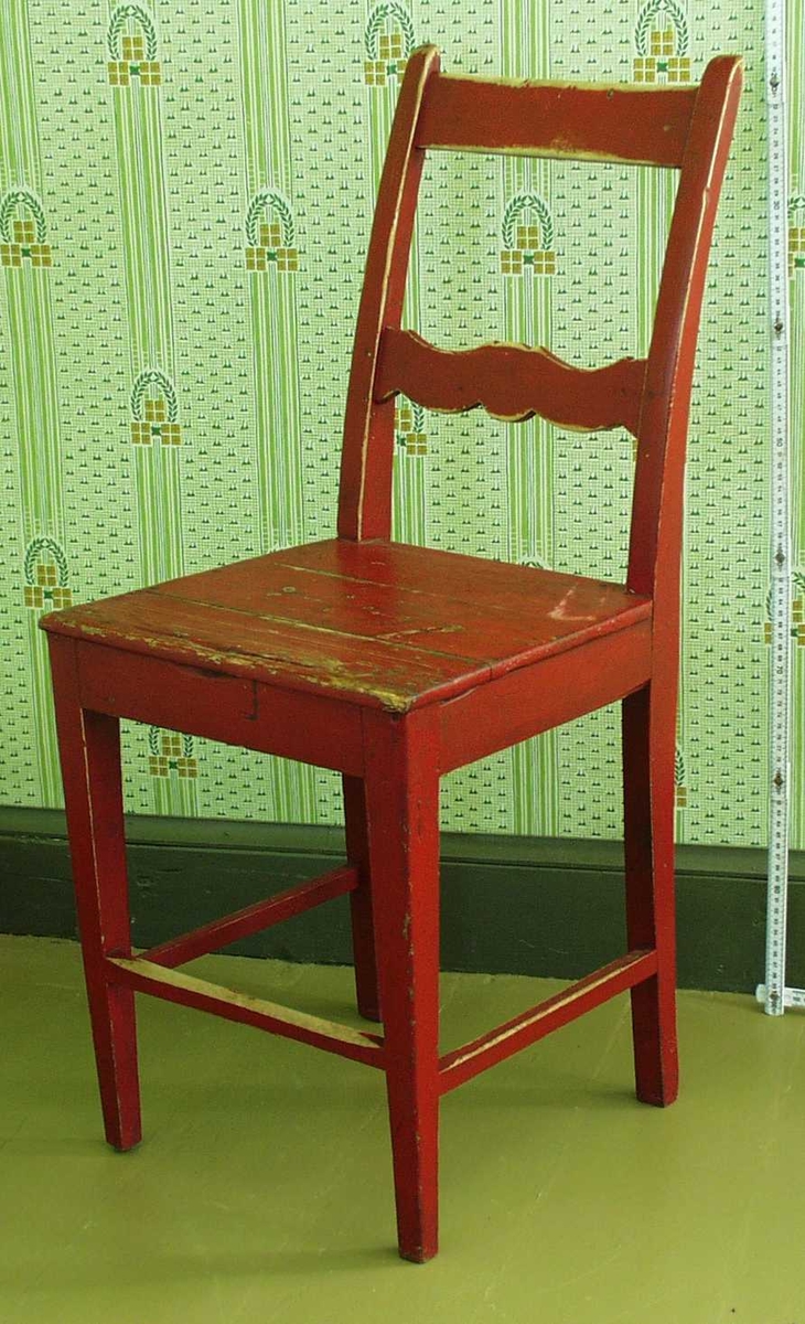 Rød pinnestol, med 2 dreide ben og 2 firkantige. Dekorert med runde skiver på bein og bølgemønster i tverrbord i ryggen.
Det er mulig at sitteplata er hjemmelaget, evt. erstattet den opprinnelige.