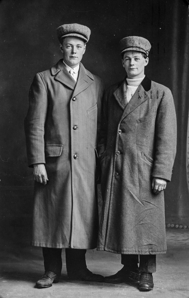 Leirfjord / Minneapolis. Julekorthilsen med bilde 1911-1912. To unge menn kledd i vinterfrakk og hatt på hodet. En av personene er J.M. Bergh.