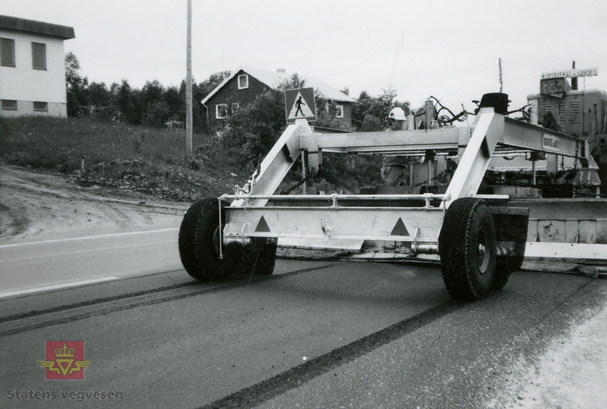 Korsbrekke og Lorck A/S, entreprenører innen asfaltering ble etablert i 1950 av Arne Vilhelm Korsbrekke og Frits Lorck. Bildet viser forvarming av veg før dekkelegging ved bruk av Heater, (propanfyring). På bildet en 1968 modell Scania Vabis lastebil (N2) med tipp. Det var i slutten av august 1974 gjort som et forsøk på å fylle asfaltsporene på den sterkt slitte rv 80. Dette var første gang dette var prøvd nord for Trondheim. Tre bilder fra samme sted, klikk på pilen til høyre.