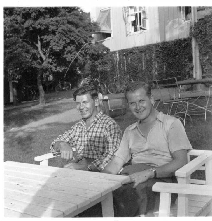 Två män i rutig skjorta respektive pike-tröja sitter i en trädgårdsmöbel.