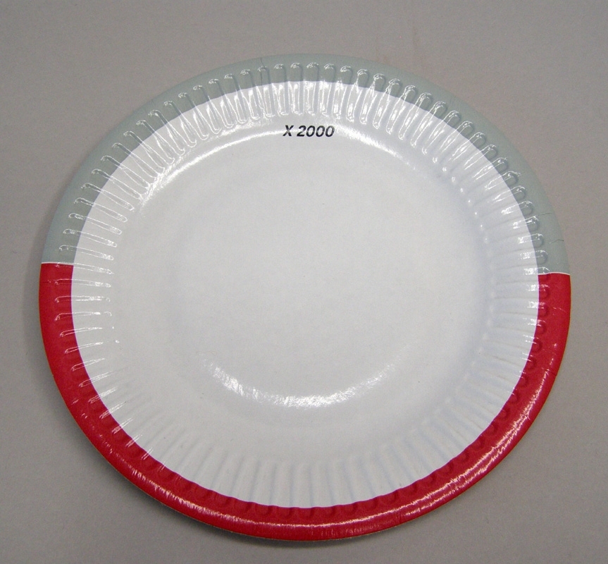 Cirkelrund tallrik av vit papp med storleken av en assiett, med en bård runt tallrikens kant i färgerna rött och grått. Med svart tryckt text står "X2000".