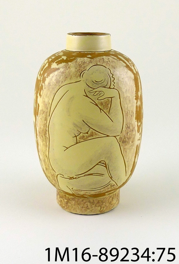 Vas av keramik i gult och brunt, kvinnofigurer på sidorna. Märkt "Vicke" Ekeby VL. Initialerna står för Vicke Lindstrand.