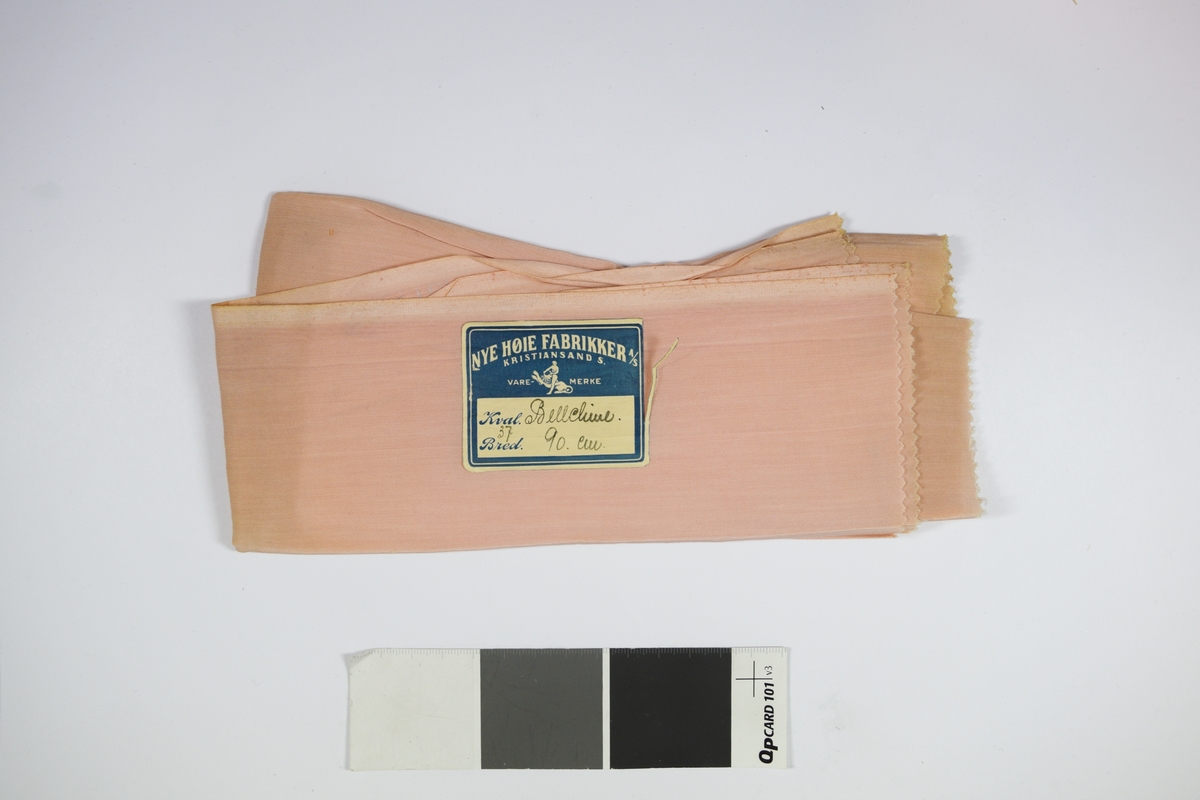 Tekstilprøve av sammenfoldet stoff, med påklistret papirlapp. Ensfarget tynt rosa tekstil.