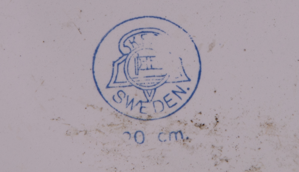 Tallrik, djup, emalj, vit med blå kant. På undersidan märke; Cirkel med emblem, KRP samt SWEDEN,  20cm.
Emaljen skadad.