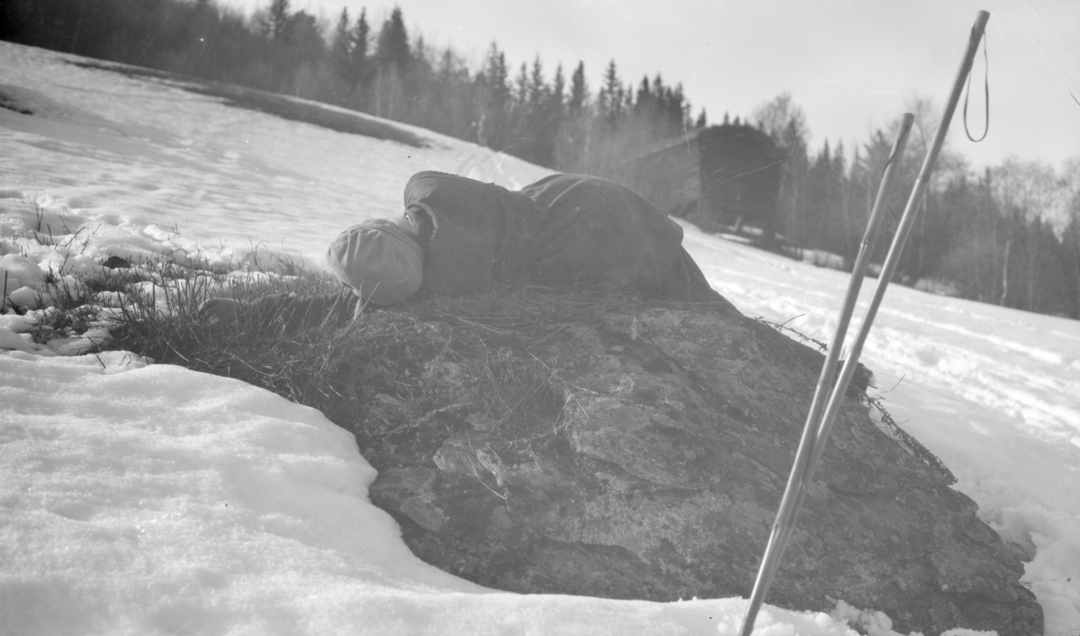 Kvinnelig skiløper hviler på stein.