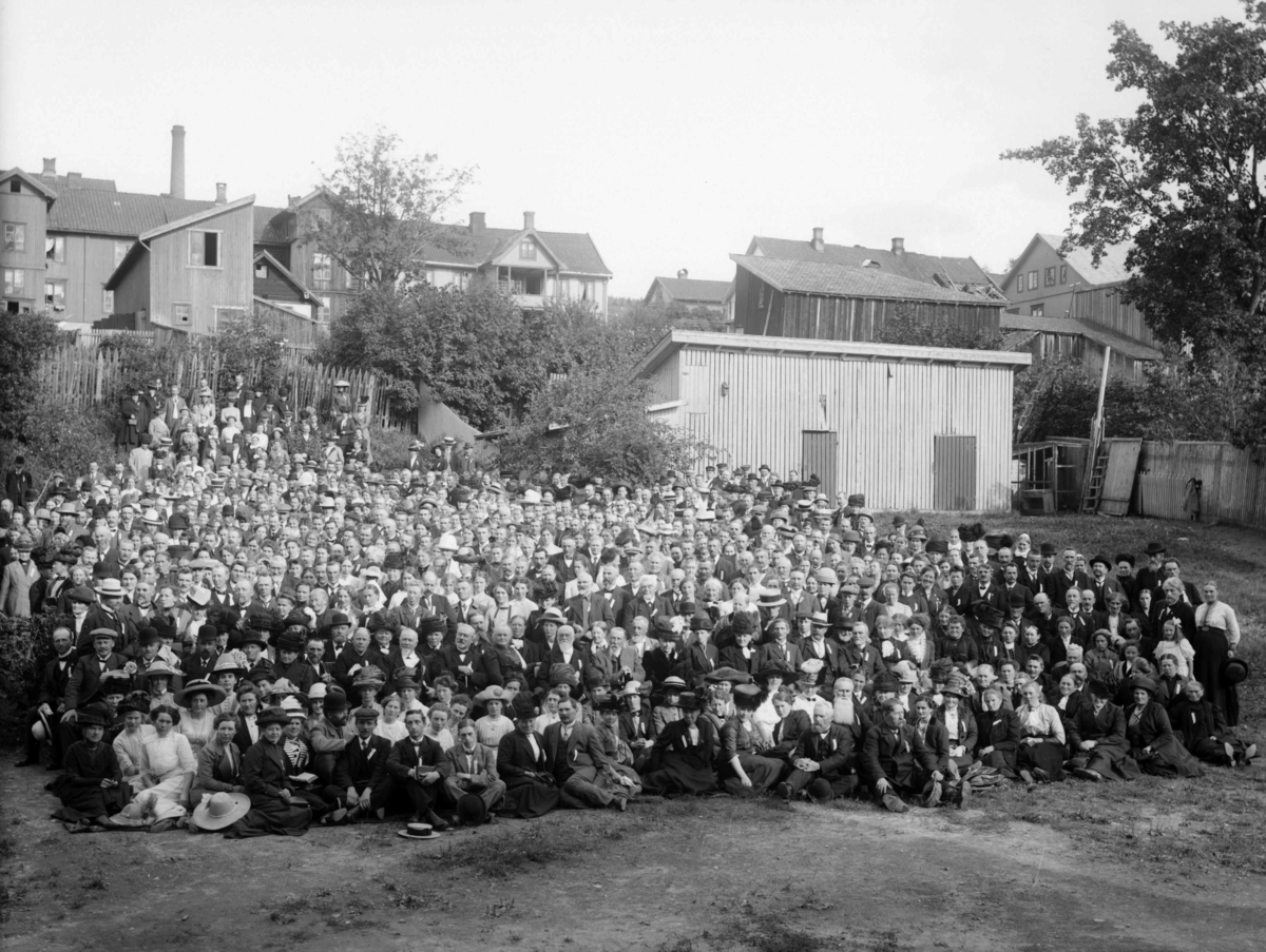 Gruppebilde av en større folkemengde - oppstilt i bakkant av Lillehammer Sparebank; det som nå er Kulturhuset Banken - og sett østover