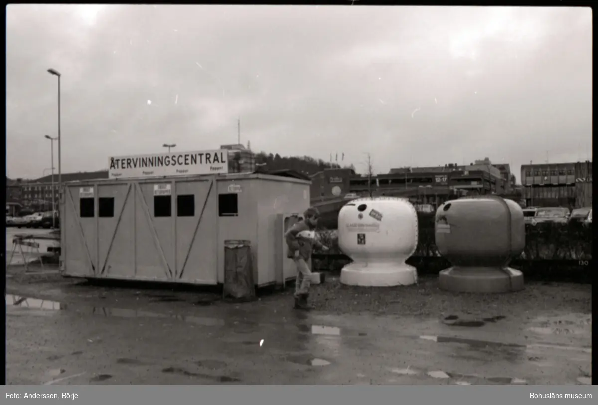 Dokumentation av en återvinningscentral vid Kampenhof i Uddevalla, i bilden syns containrar för glas och papper. Personer lämnar sitt avfall i dessa. 