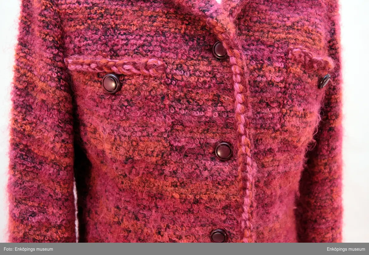 Dräkt jacka vävd i röd melerat ullgarn med flätade kantband i samma garn. 4 fickor fram. Plagget har 9 st mörkröda knappar.