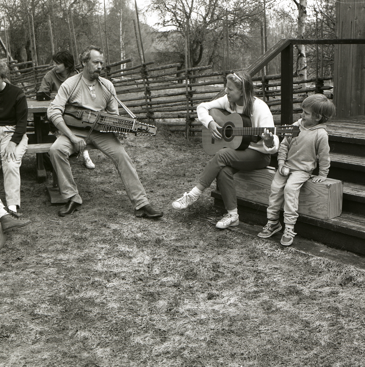 En grupp människor har samlats för att lyssna på två personer som spelar nyckelharpa och gitarr, 14 maj 1986.