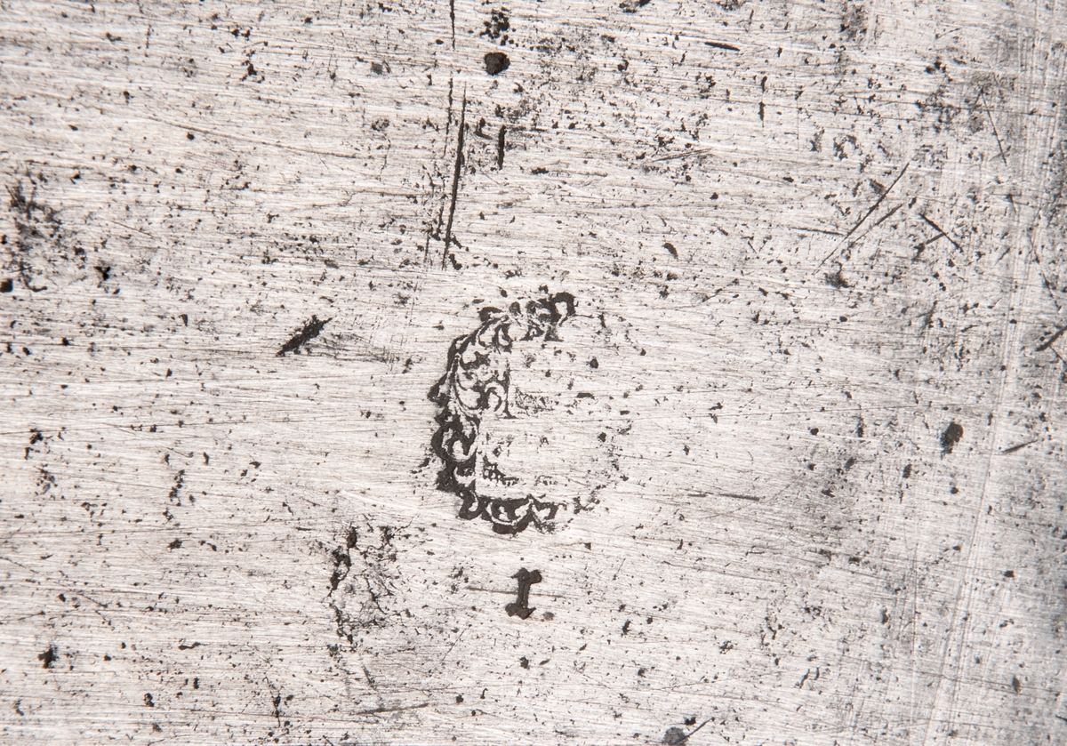 Balja av tenn, fyrsidig med gavelsidorna uppdragna i spets på mitten, samt med handtagsringar i lejongap. Låg fot.
I botten stämplat "r" samt tre kronor och mästarstämpel som liknar H.G. Pschorn i Stockholm.