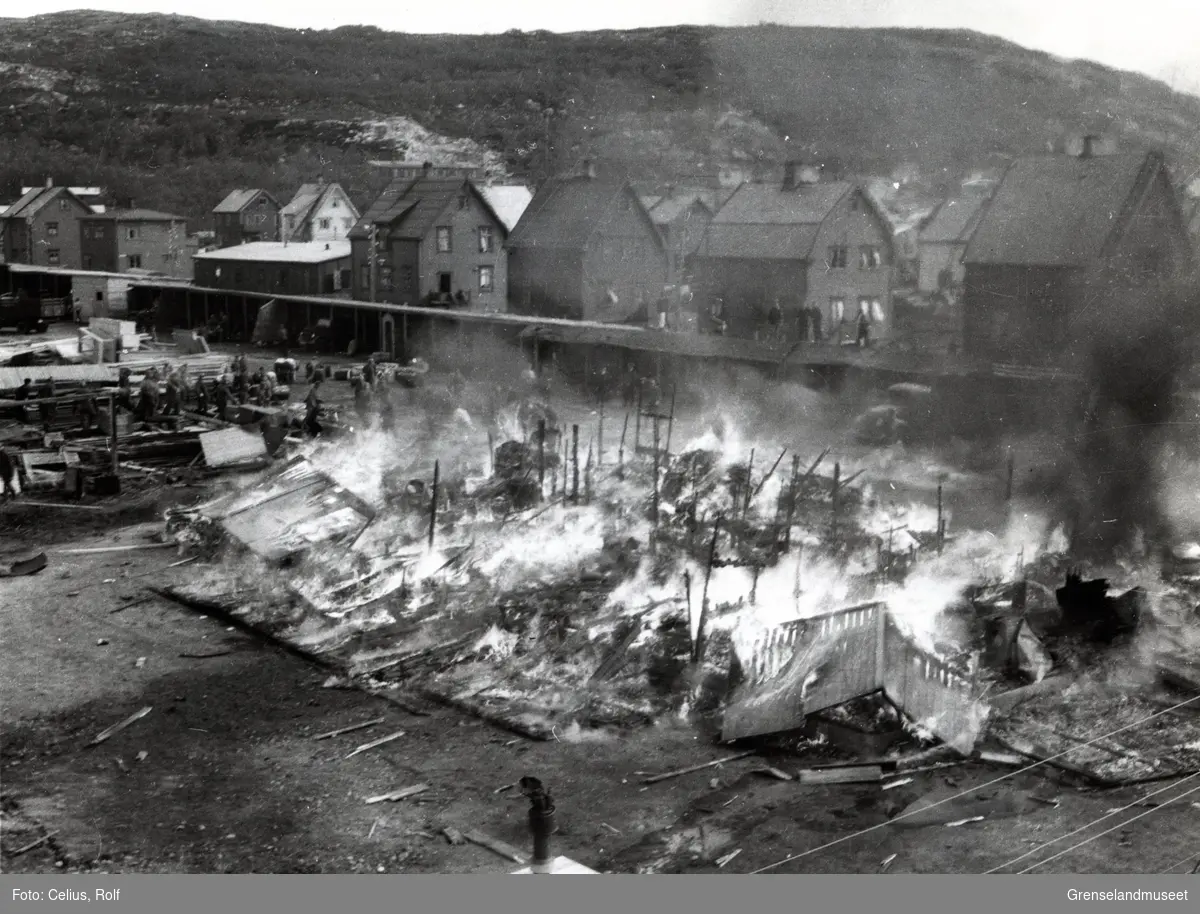 Tysk panserdivisjonbrakke truffet av bomber 27.06.1941. Bildet er tatt fra  2. etasje i Celius sitt i Klavenessgate. Brakken som brenner står på fotballplassen. 