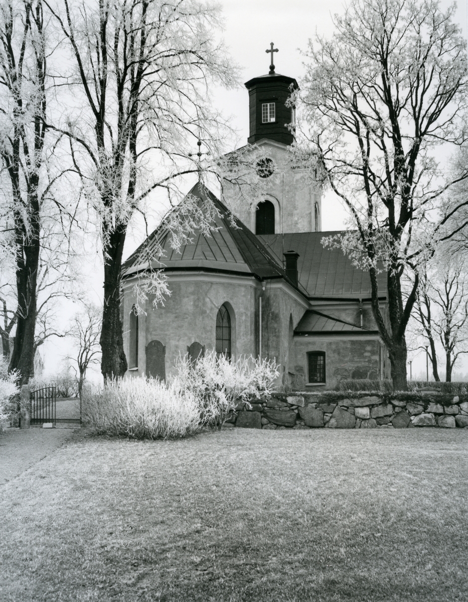Lundby sn.
Lundby kyrka, exteriör med stenmuren framför. 1975.