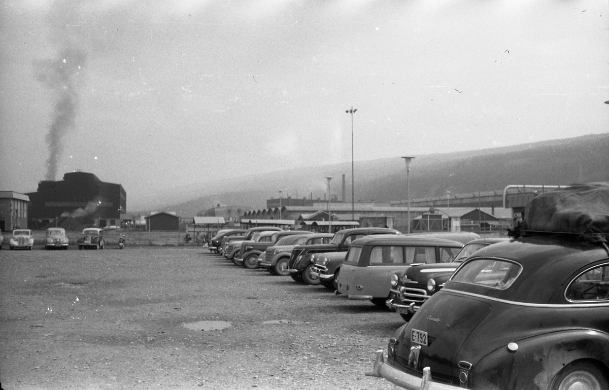 Avfotografert bilde fra en parkeringsplass foran et uidentifisert fabrikkanlegg. Bilen med reg.nr. E-792 er iflg. informant en Chevrolet, årsmodell 1946-48 Dernest en Vauxhall Velox 1951-55.