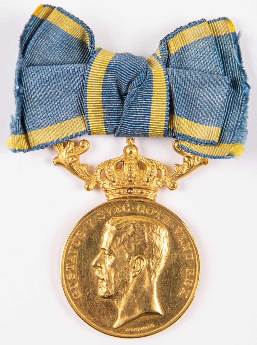 Medalj.
Guld, av A. Lindberg.
Konsulinnan Antonie Rettigs Illis Quorum, diam 3,2cm.
På ena sidan Gustav V i reliefprofil från vänster. På den andra sidan "Antonie Rettig. N. von Eckerman".
Vid ovankanten krona samt blågult band.