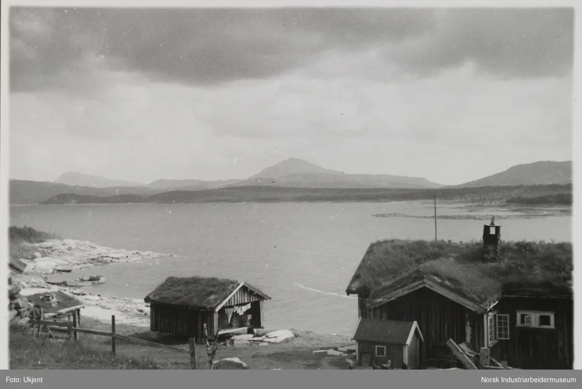 Husbygninger står ved vannkanten, innsjøen Møsvatn