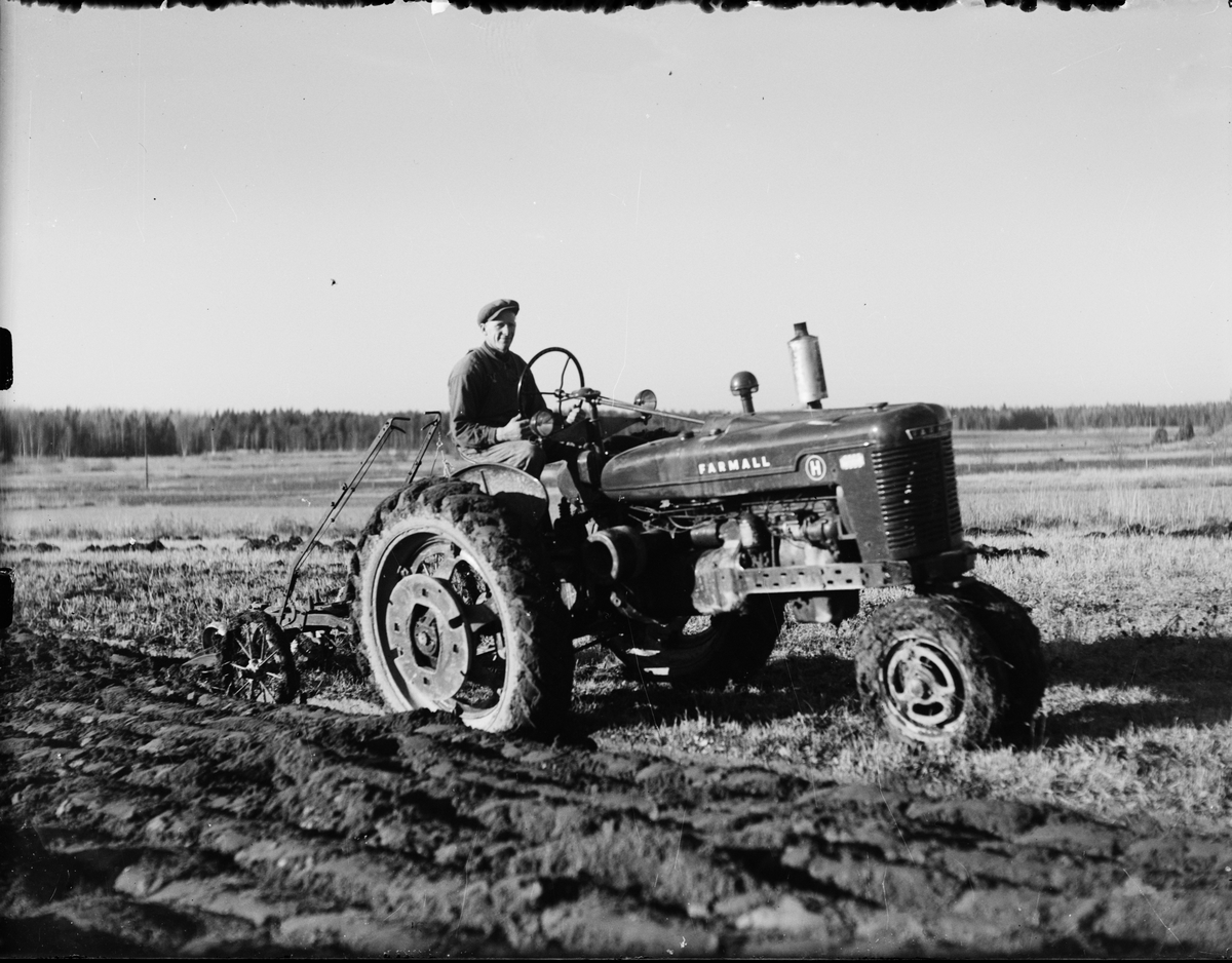 Man kör traktor med plog på åkern, Östhammar, Uppland